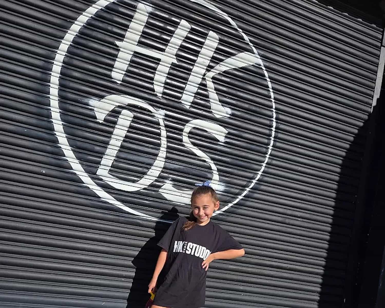 A young HK Dance Studios dancer in front of the studio shutter